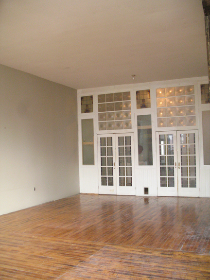 Photograph highlighting the hardwood floors, 12' 4" ceilings and the artist designed glass wall of loft 2F at the warehouse in Philadelphia