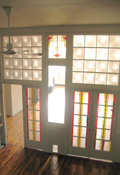 Light shimers through the two sets of stained glass double doors that devide the front and center spaces of loft 2F in this photograph.