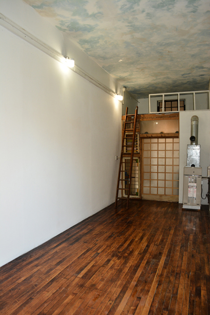 There is a sliding glass door leading to the rest of the loft ans a library ladder leading to a storage area in the rear room of loft 2F at the Warehouse in Philadelphia PA